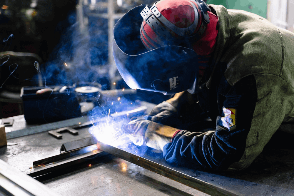 man in warehouse welding sheet metal for fabrication